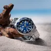 A watch on a beach with driftwood and the ocean in the background. Anteprima dell’immagine prodotto