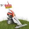 A red and silver walk-behind mower with a cutting bar is shown in tall green grass. Produktbild-Vorschau