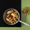 A frying pan with salmon and sweet potato fries on a stovetop, with dill and spices nearby. Podgląd zdjęcia produktu
