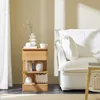 A wooden nightstand with books, a vase, and a cup sits next to a white sofa in a well-lit room. Produktbild-Vorschau