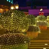 A nighttime outdoor scene with bushes decorated with warm white LED lights, leading up a set of stairs. Náhled obrázku produktu