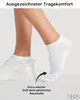 A person's legs wearing white socks and sneakers. Produktbild-Vorschau