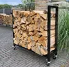 A metal firewood rack filled with logs, placed on a brick patio. Produktbild-Vorschau