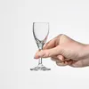 A hand holding a small clear glass. Náhľad obrázku produktu