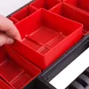 A hand is shown placing a red plastic compartment into a black organizer box. Náhľad obrázku produktu