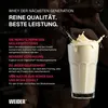A woman drinks from a bottle of whey protein, with a glass of the protein shake next to her. Produktbild-Vorschau