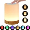 A touch-dimmable LED night light with a wood-grain base is shown with a hand touching the top, and smaller circular images of the light in different colors. Produktbild-Vorschau