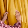 Hands touching a mustard yellow curtain. Produktbild-Vorschau