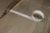 A close-up view of a measuring tape placed on a table saw, with the tape extending towards the saw blade. Náhled obrázku produktu