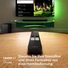 A soundbar and remote control are displayed on a wooden table in front of a television screen. Voir les images du produit