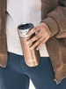 A person holding a bronze Contigo travel mug. Produktbild-Vorschau