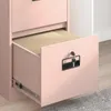 A close-up of a pink filing cabinet with one drawer pulled out, revealing hanging files inside. The drawer has a black handle and a lock with a key. Voir les images du produit