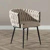A beige upholstered chair with black metal legs is shown against a light gray wall and a wooden floor. Produktbild-Vorschau
