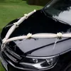 Cremefarbene Organza-Girlande mit Rosenblüten in V-Form auf der Motorhaube eines schwarzen Autos als elegante Hochzeitsdekoration befestigt. Produktbild-Vorschau