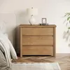A bedside table with a lamp and a framed picture on top, next to a bed. Produktbild-Vorschau