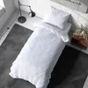 A neatly made bed with white bedding in a room with a lamp and a rug. Produktbild-Vorschau