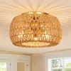 A close-up view of a woven rattan ceiling light fixture with a gold-colored base, mounted on a white ceiling. Anteprima dell’immagine prodotto
