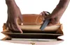 A person's hands are shown placing a GPS tracker into a leather briefcase that contains a laptop. Náhľad obrázku produktu