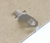 A close-up shot of a metal clip attached to a brown board, likely the back of a picture frame. Produktbild-Vorschau