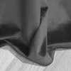 A close-up view of a dark gray velvet curtain draped over a light-colored wooden surface. Podgląd zdjęcia produktu