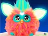 A close-up studio shot of a colorful, fluffy toy with large eyes and glowing ears against a blue background. Podgląd zdjęcia produktu