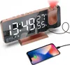 A rose gold digital alarm clock with a projected display and a smartphone charging next to it. Produktbild-Vorschau