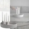 A hand lighting a candle on a round candle holder on a coffee table. Produktbild-Vorschau