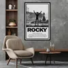 A movie poster for Rocky is displayed on a wall above a chair and a coffee table. Produktbild-Vorschau