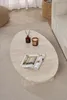 A travertine coffee table with a magazine, a candle, and a diffuser on it, placed on a rug in a living room setting. Anteprima dell’immagine prodotto