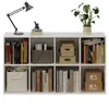 A white shelving unit filled with books, decorative boxes, a plant, and a lamp. Náhľad obrázku produktu