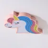 A close-up, angled shot of a pink unicorn-shaped ceiling lamp mounted on a white ceiling. Produktbild-Vorschau