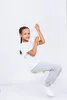 A young girl is sitting on a yellow swing, holding onto a white rope, against a plain white background. Náhled obrázku produktu