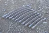 Several curved metal pieces laid out on a gravel surface. Náhled obrázku produktu