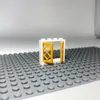 A LEGO window frame with yellow shutters is placed on a gray LEGO baseplate. Produktbild-Vorschau