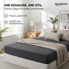 A bedroom scene featuring a bed with a dark gray fitted sheet and a beige throw blanket. Produktbild-Vorschau