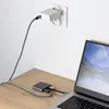 A USB-C adapter hub is connected to a laptop, with a power adapter plugged into a wall socket. Produktbild-Vorschau