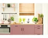 A kitchen counter with pink cabinets, a sink, and various kitchen items. Voir les images du produit