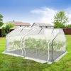 A small greenhouse with tomato plants inside, set up in a backyard with houses and trees in the background. Voir les images du produit