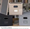 Three storage boxes in different colors (beige, black, and gray) are displayed on a wooden surface, with a bookshelf in the background. Anteprima dell’immagine prodotto