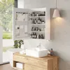 A modern bathroom vanity with a sink, mirror cabinet, and bathtub. The mirror cabinet is open, showcasing various toiletries and accessories. The vanity has a wooden countertop and white sink. Náhľad obrázku produktu