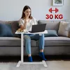 A woman is sitting on a couch using a laptop on a mobile desk. Voir les images du produit