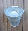 A galvanized metal bucket is hanging on a wooden fence. Produktbild-Vorschau