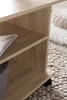A close-up view of a wooden shelf unit with a basket and a folded newspaper on it, placed on a textured rug. Produktbild-Vorschau