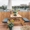 A rooftop patio with a picnic table and seating, surrounded by a bamboo fence. Produktbild-Vorschau