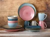 A collection of colorful ceramic dishes and mugs arranged on a wooden surface. Náhľad obrázku produktu