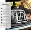 A dog crate is placed in the trunk of a car, with a dog sitting next to it. Náhled obrázku produktu