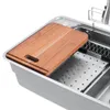 A close-up view of a stainless steel kitchen sink with a wooden cutting board placed on top. Podgląd zdjęcia produktu