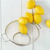 Lemons are placed on and around a metal sieve on a white wooden surface. Anteprima dell’immagine prodotto