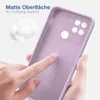 A hand is touching a purple phone case, highlighting its matte surface and soft grip texture. There is also a small pile of fluffy material in the background. Produktbild-Vorschau