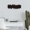 A wall-mounted coat rack with five movable hooks is shown on a light gray wall above a white desk. A cactus plant is visible to the right of the desk. Náhľad obrázku produktu